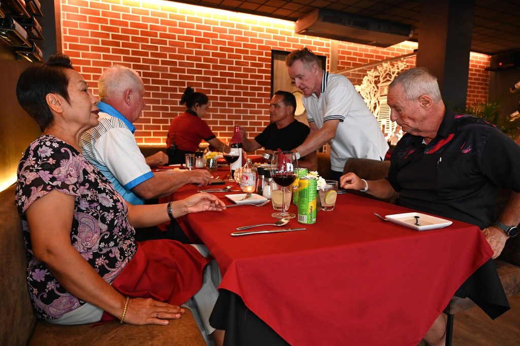 DSC 7059 A group of friends laugh and chat over drinks and dinner at a cozy restaurant with warm brick walls and a red tablecloth setting the scene
